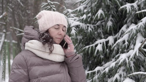 Outdoor winter portrait. Beautiful woman 45 years old talking on a cell phone in a snowy winter park