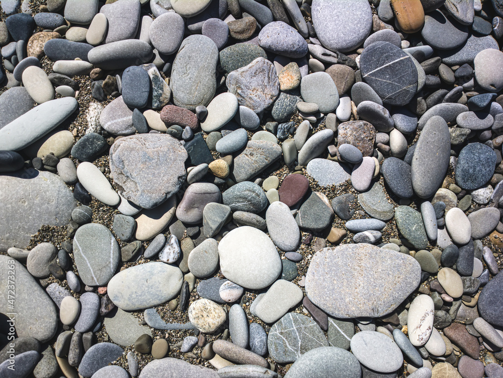 Sea stones background with small pebbles or stone in garden or in the seaside or on a beach. A close up view of rounded smooth polished pebble stones Sea stones background with small pebbles or stone in garden or in the seaside or on a beach. A close up view of rounded smooth polished pebble stones