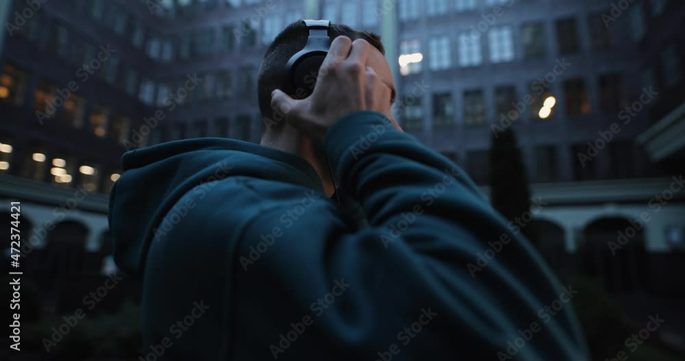 Man puts on headphones in a city street slow motion, profile view Man puts on headphones in a city street slow motion, profile view
