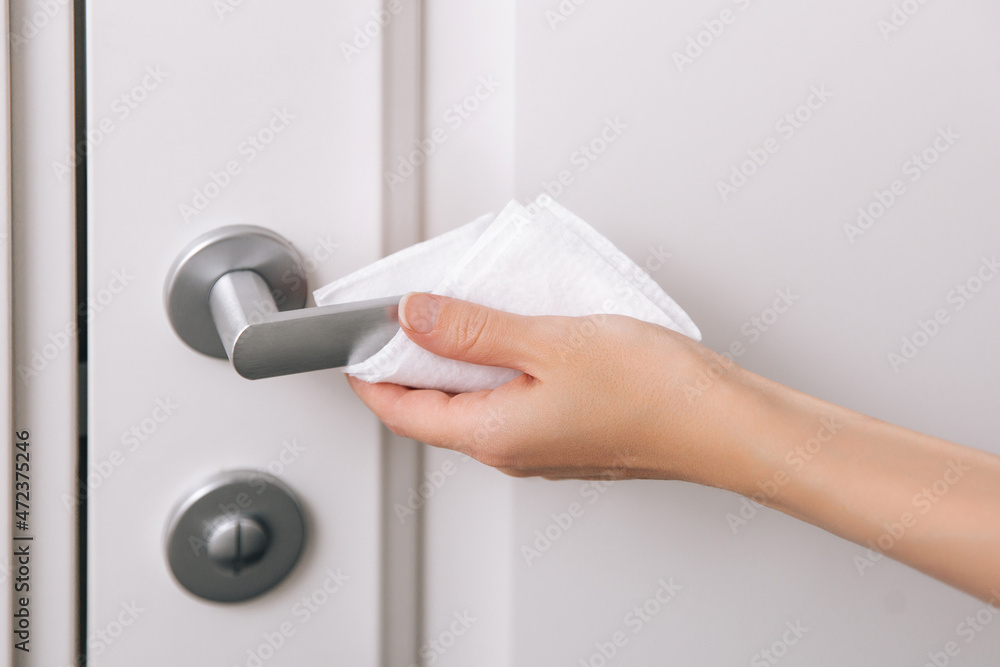 Cleaning door handles with an antiseptic wet wipe and gloves. Woman hand using towel for cleaning home room door link. Sanitize surfaces prevention in hospital and public spaces against corona virus. Cleaning door handles with an antiseptic wet wipe and gloves. Woman hand using towel for cleaning home room door link. Sanitize surfaces prevention in hospital and public spaces against corona virus.