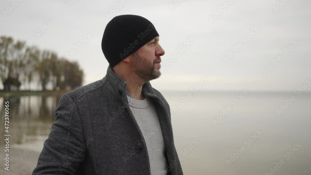 middle aged man standing by the sea in winter and looking relaxed into the distance middle aged man standing by the sea in winter and looking relaxed into the distance
