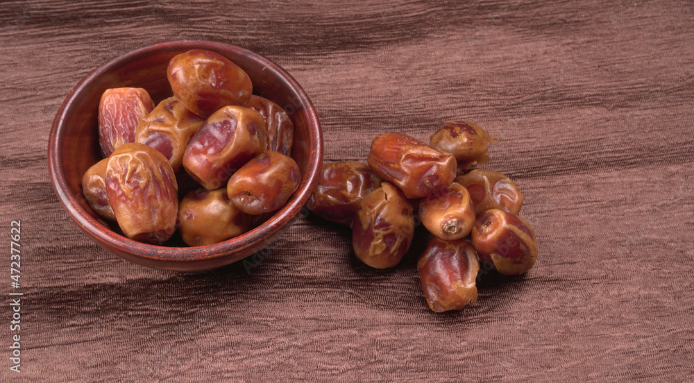 Obraz premium Dates in wooden bowl on background. dried dates fruit.