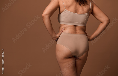 Rear view of female body with flaws and imperfections isolated on beige background with copy ad space. Body positivity  love to your body  self-confidence and the concept of self-acceptance