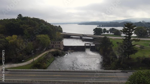 Aerial view of old wheelhouse and dam leading to expansive lake. Misty and clouded horizon with gleaming sun spots on the water.  photo