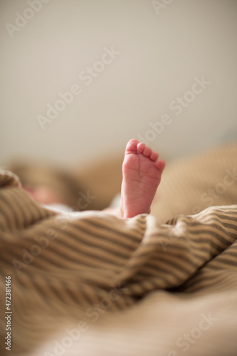 copy space shot of a cute newborn baby foot on a brown beige blanket in bed with a bokeh blurred background