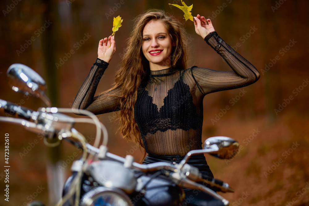 Obraz premium A beautiful woman with long hair on a chopper motorcycle in autumn landscape.