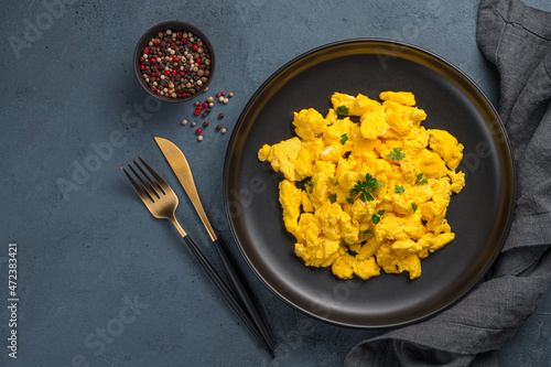 A portion of scrambled eggs with parsley on a dark background. Top view, horizontal. A recipe for home cooking. photo
