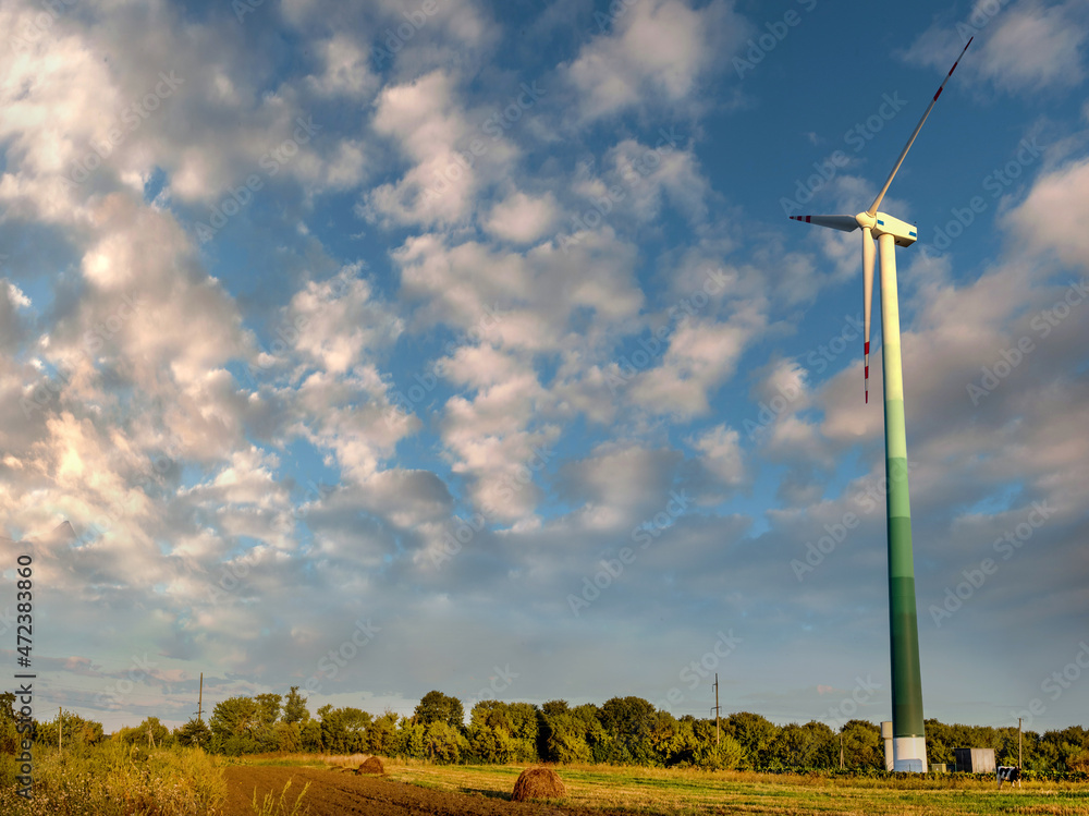 Fototapeta premium wind turbines in a field with beautiful clouds, bottom view, alternative energy