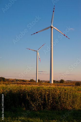 two wind turbines in field with blue sky evening light, Eco green power