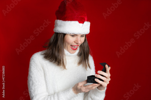 Santa girl is opening a Christmas gift isolated on red background  surprise for Christmas