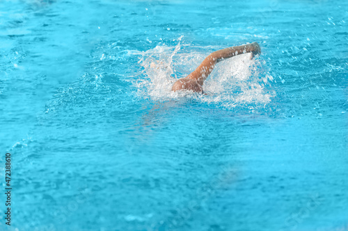 A swimmer swims quickly under the water in the pool. Blurry movement.