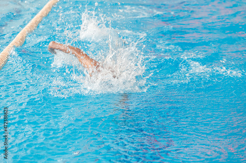 A swimmer swims quickly under the water in the pool. Blurry movement.