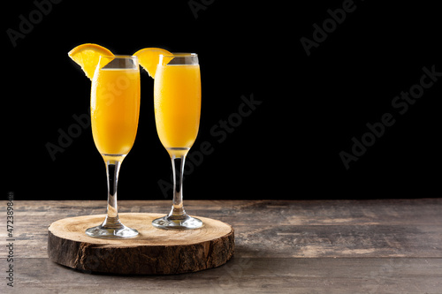 Orange mimosa cocktail on wooden table. Copy space photo