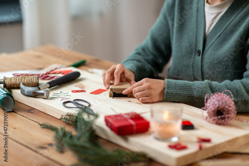 winter holidays and hobby concept - close up of woman packing christmas gift in craft wrapping paper or making advent calendar at home