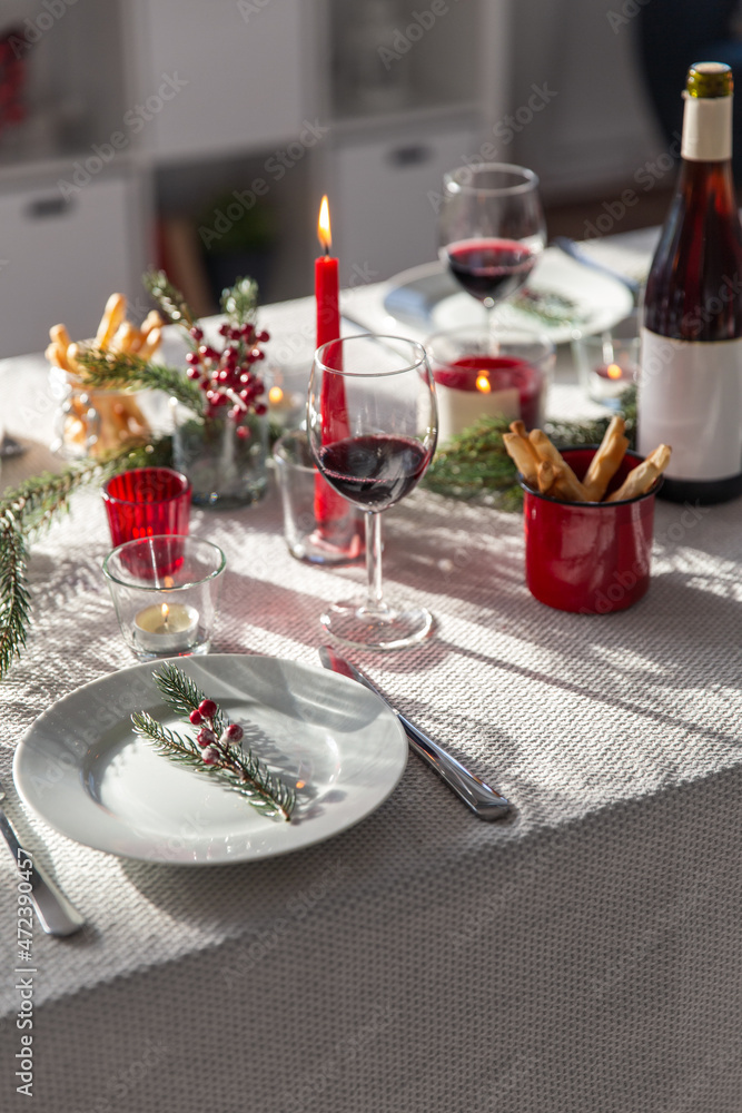 winter holidays, dinner party and celebration concept - christmas table serving with candles, crockery and wine at home winter holidays, dinner party and celebration concept - christmas table serving with candles, crockery and wine at home