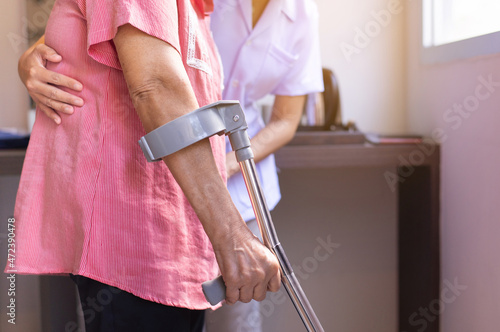 Nurse helping senior woman hand using crutches trying to walk,Care nursing home concept