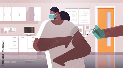 doctor hand vaccinating african american female patient in medical mask fight against coronavirus vaccine development