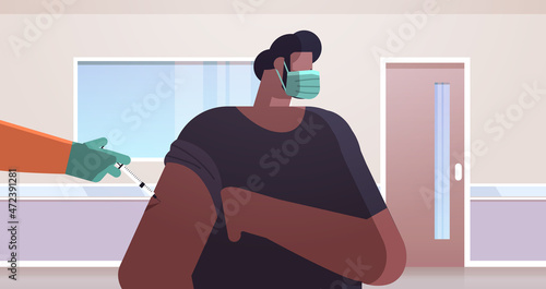 doctor hand vaccinating african american male patient in medical mask fight against coronavirus vaccine development
