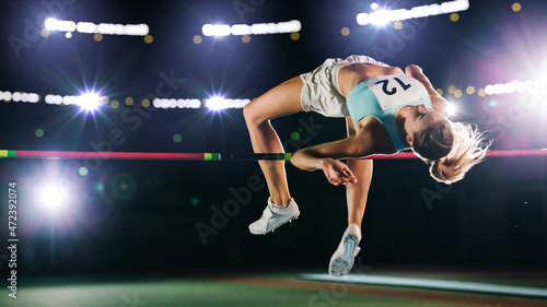 High Jump Championship: Professional Female Athlete on World Championship Successfully Jumping over Bar. Shot of Competition on Stadium with Sports Achievement Experience. Determination of Champion. photo