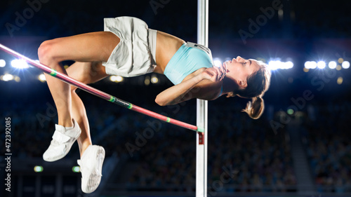 High Jump Championship: Professional Female Athlete on World Championship Successfully Jumping over Bar. Shot of Competition on Stadium with Sports Achievement Experience. Determination of Champion.