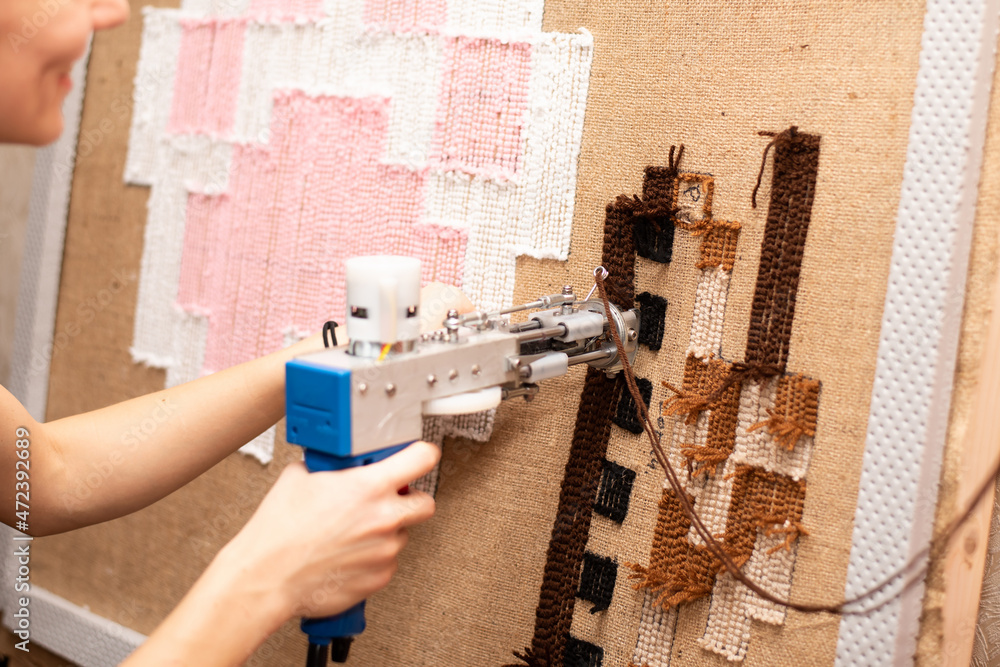 The process of making a small tank carpet using a tufting gun on burlap. Stock Photo Adobe Stock
