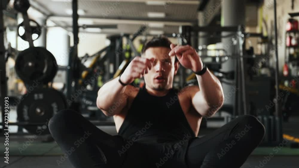 Young sportive strong man in black wear doing abs in the gym Young sportive strong man in black wear doing abs in the gym