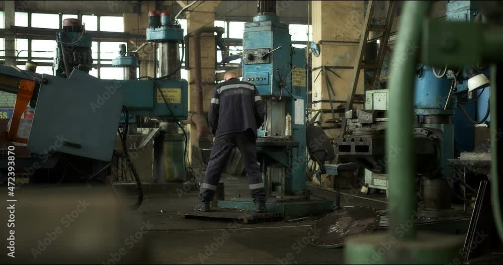 A professional worker in uniform at a lathe. Metal shavings. Production of heavy industry products and large metal structures. Modern steel industry. A professional worker in uniform at a lathe. Metal shavings. Production of heavy industry products and large metal structures. Modern steel industry.