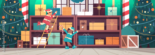 mix race elves preparing gifts for new year and christmas holidays celebration modern workshop interior