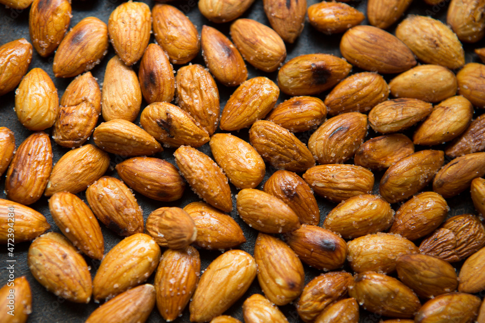Filled frame background wallpaper shot of a bunch of crunchy roasted almonds with sea salt on a black background Filled frame background wallpaper shot of a bunch of crunchy roasted almonds with sea salt on a black background