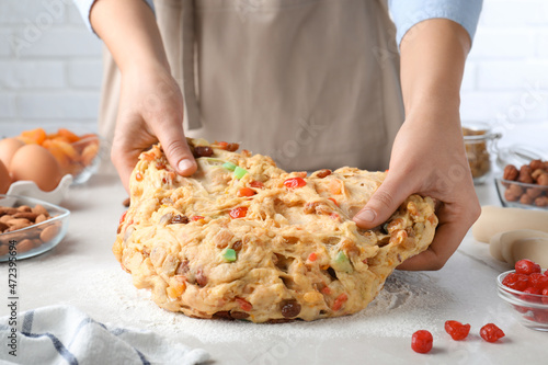 Fototapeta Naklejka Na Ścianę i Meble -  Woman kneading dough with candied fruits and nuts for Stollen at white table, closeup. Baking traditional German Christmas bread