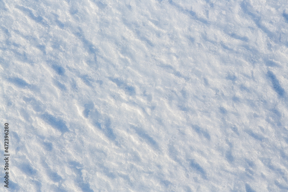 Natural snow texture. The surface of the snow crust. Snowy ground. Winter background with snow patterns. Perfect for Christmas and New Year design. Closeup top view.