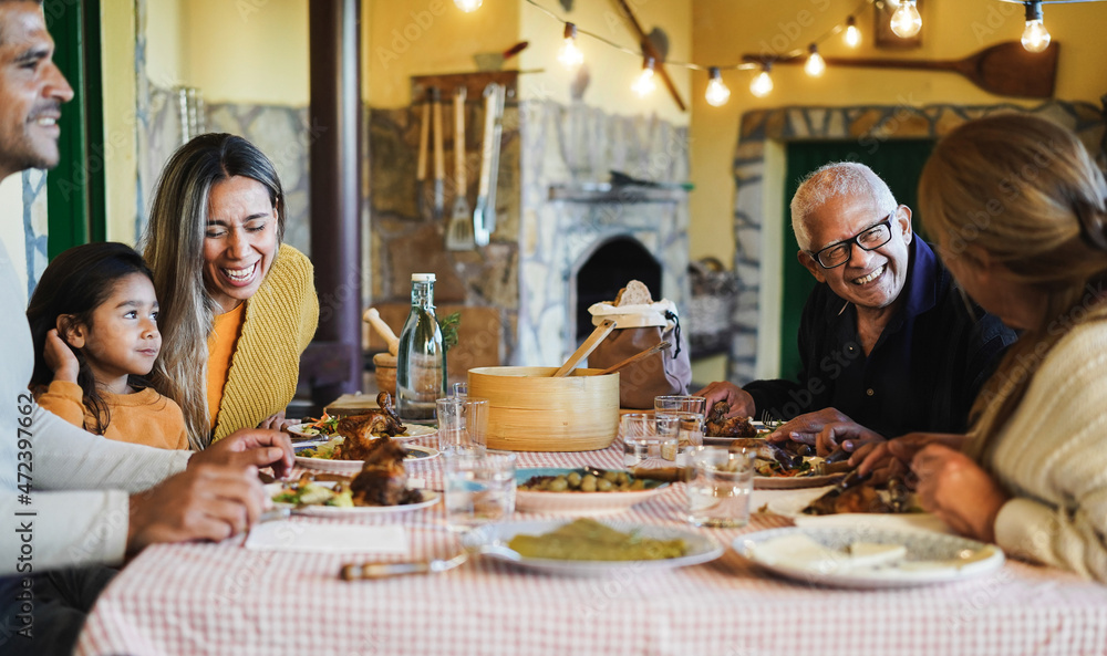 Happy latin family having fun eating together at home - Focus on grandfather face Happy latin family having fun eating together at home - Focus on grandfather face