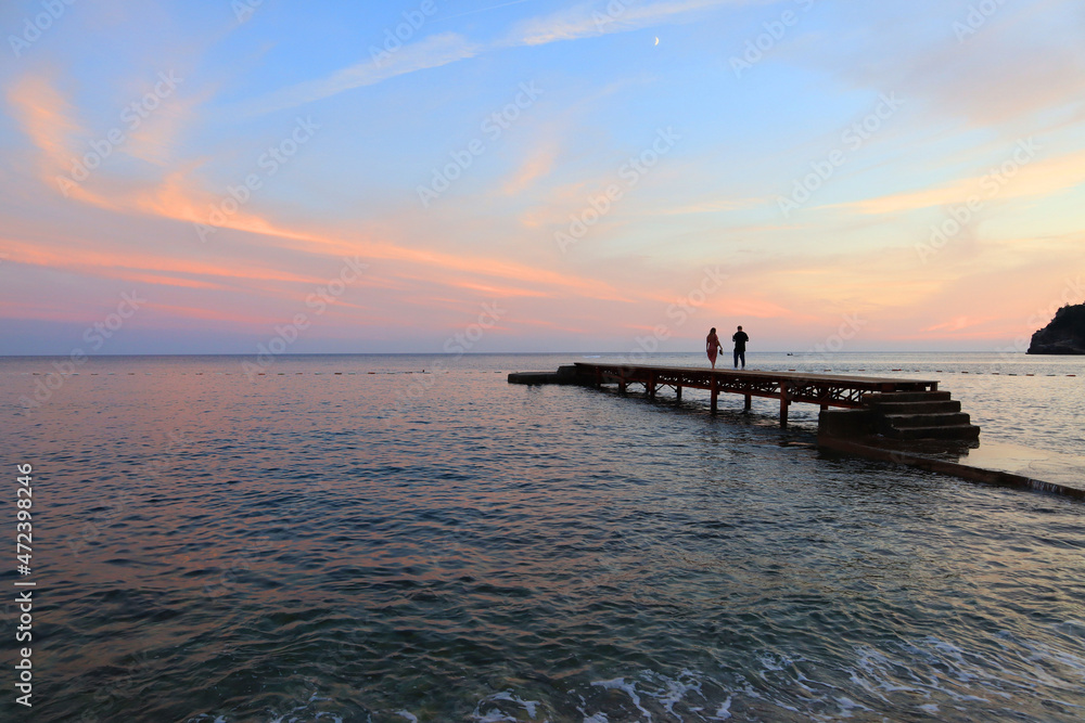 People in front of sunset sky at pier in Budva, Montenegro
