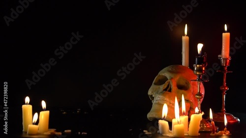 Skull head with candle lights set on black background. Old brass candlesticks. Smoke. The concept of mysticism and ritual. The religion of dark magic and Satanism. Put out the candles slow motions