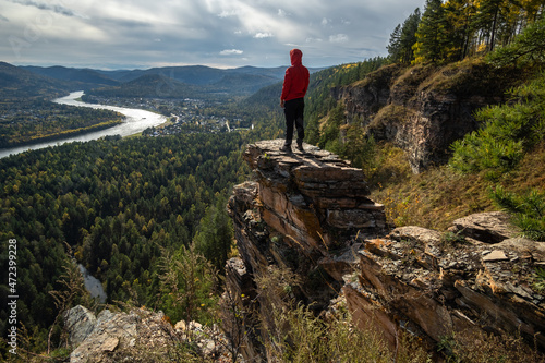 A man stands on the edge of a cliff and admires the view of the river