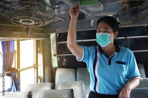 Asian female passenger wear hygienic face mask   stand on bus. Feel lonely. Concept  Protecting self in using public transport during the Coronavirus  Covid-19 epidemic. Keep social distancing.