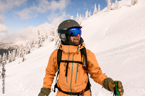 man skier with beard wearing yellow jacket and ski helmet and goggles © fesenko