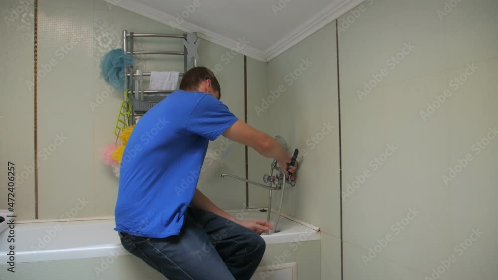 Man repairing a tap in bathroom