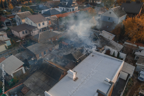  Severe fire in a private house. the roof is on fire. Thick smoke in the sky. Photo from the drone. Rescuers put out the fire.
