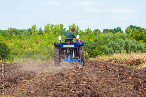 Fényképezés A blue compact tractor is harvesting potatoes in the field