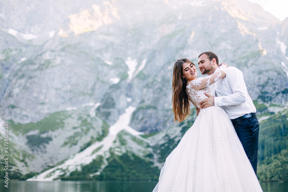 The bride and groom by the lake in the mountains. Newlyweds toge