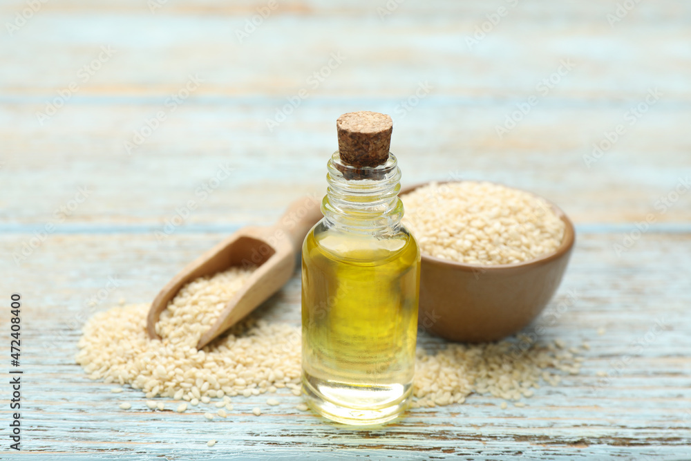 Fresh sesame oil and seeds on light blue wooden table, closeup Fresh sesame oil and seeds on light blue wooden table, closeup