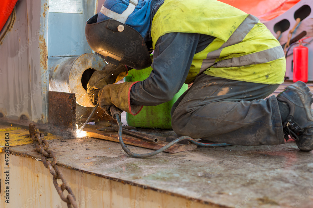 Deck crew performing welding of lashing stoppers for safe cargo securing. Deck crew performing welding of lashing stoppers for safe cargo securing.