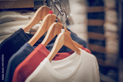 T-shirts on hangers. Stacks of clothes. Shopping in store. Clothes on hangers in shop for sale