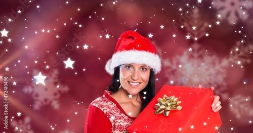 Composite image of happy woman with christmas gift against starry background with copy space