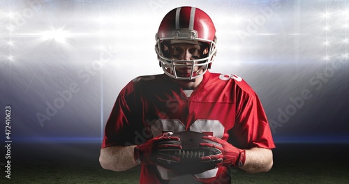 Portrait of confident male athlete holding american football at illuminated stadium © vectorfusionart