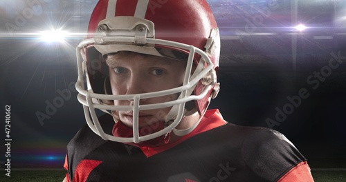 Portrait of young male american footballer wearing red helmet at illuminated stadium