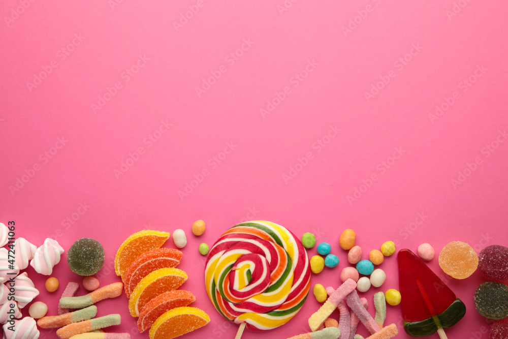 Colorful candies lollipops and jelly on pink background. Top view. Sweets with copy space
