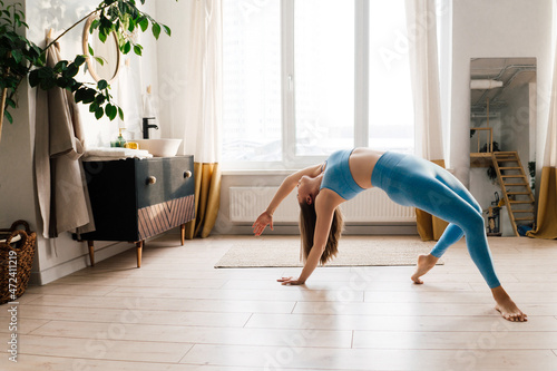 Young woman practicing yoga indoor. Light interior.