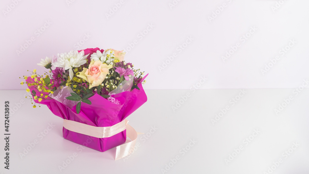 A beautiful low bouquet of different flowers, roses, chrysanthemums, gypsophila in crimson, lilac, pink shades